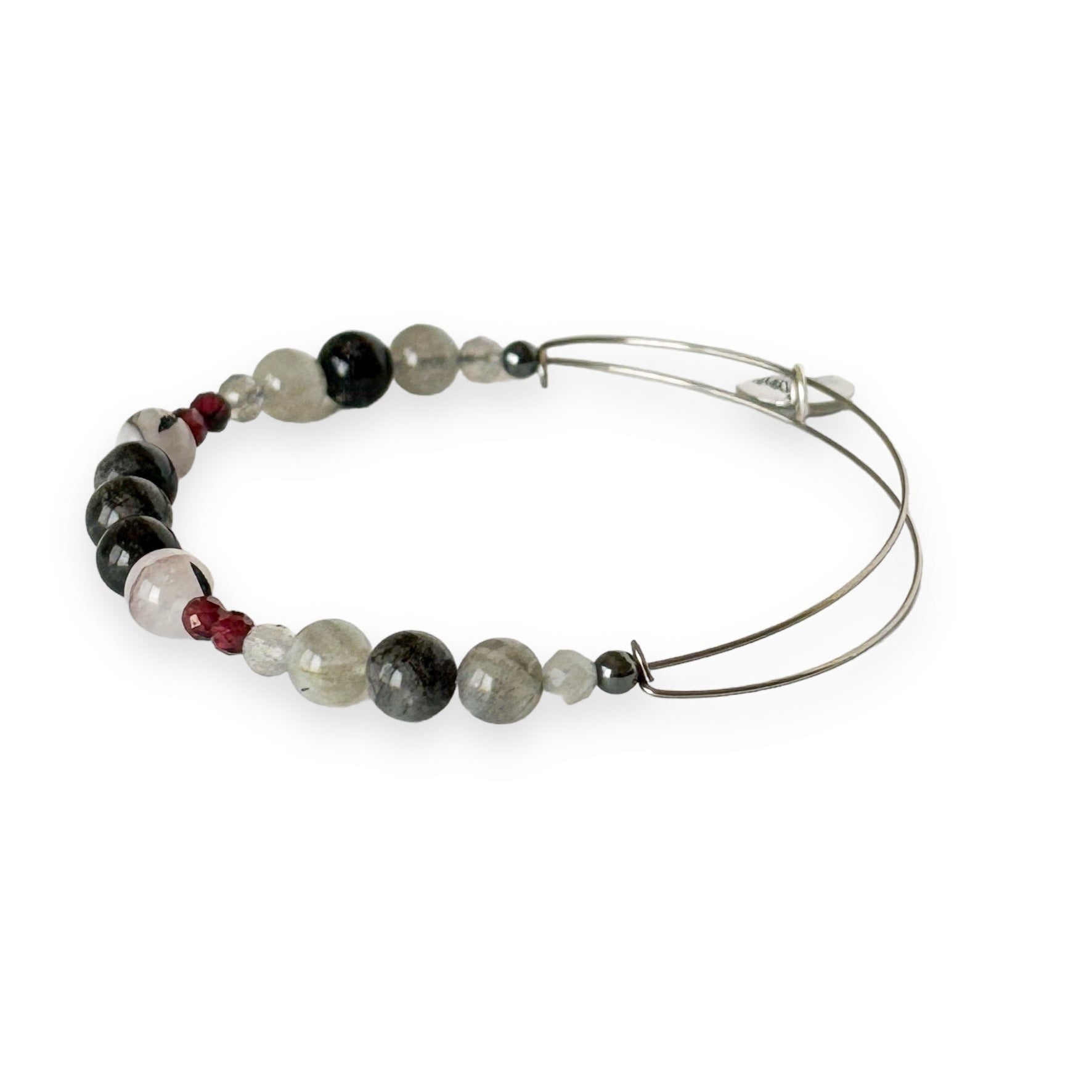 Close-up of crystal bangle bracelet with red garnet, tourmaline in quartz, and labradorite