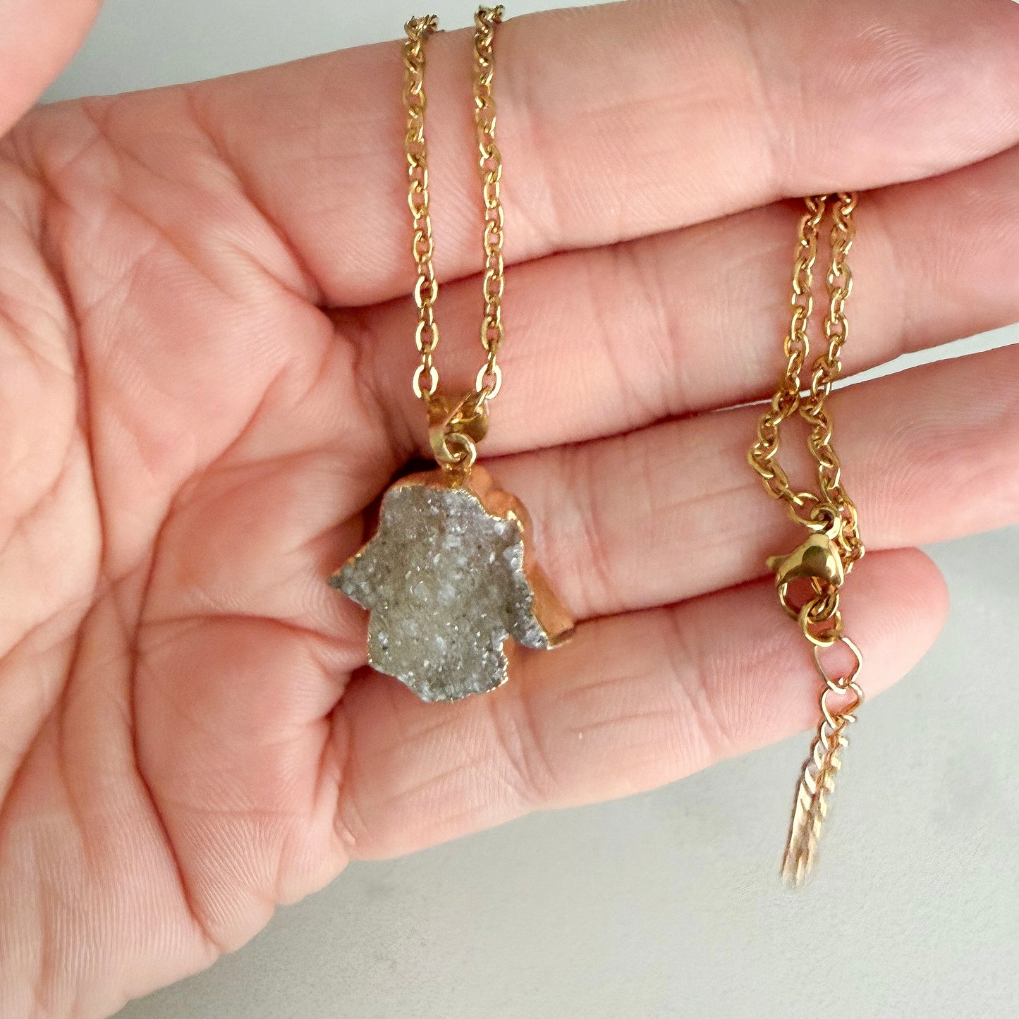 Close up of gold plated Hamsa drusy hand pendant highlighting natural crystal sparkle and texture.