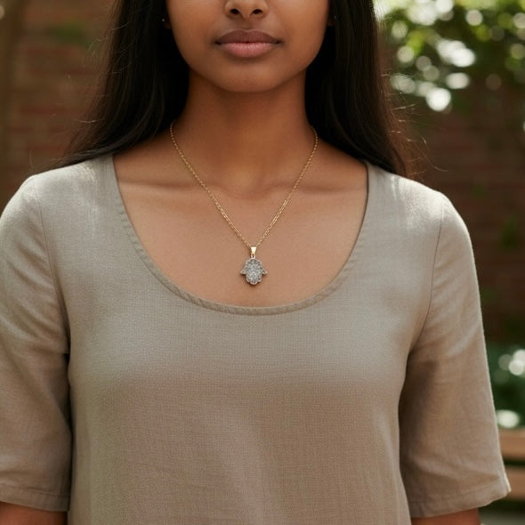 Modeled view of a gold plated Hamsa drusy hand pendant necklace on a PVD gold plated stainless steel chain, shown in an AI generated lifestyle image.