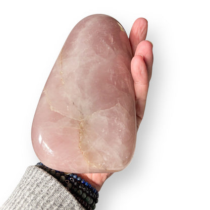 Hand holding extra large polished Rose Quartz stone for size reference.