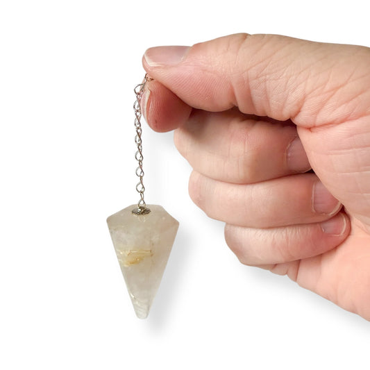 Hand holding a golden rutile milky quartz pendulum against a white background