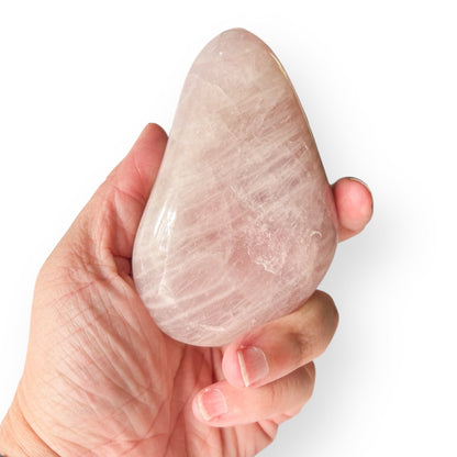 Hand holding large polished Rose Quartz stone showing natural size and tone.