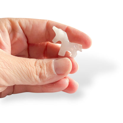 Hand holding small calcite unicorn carving for size reference.