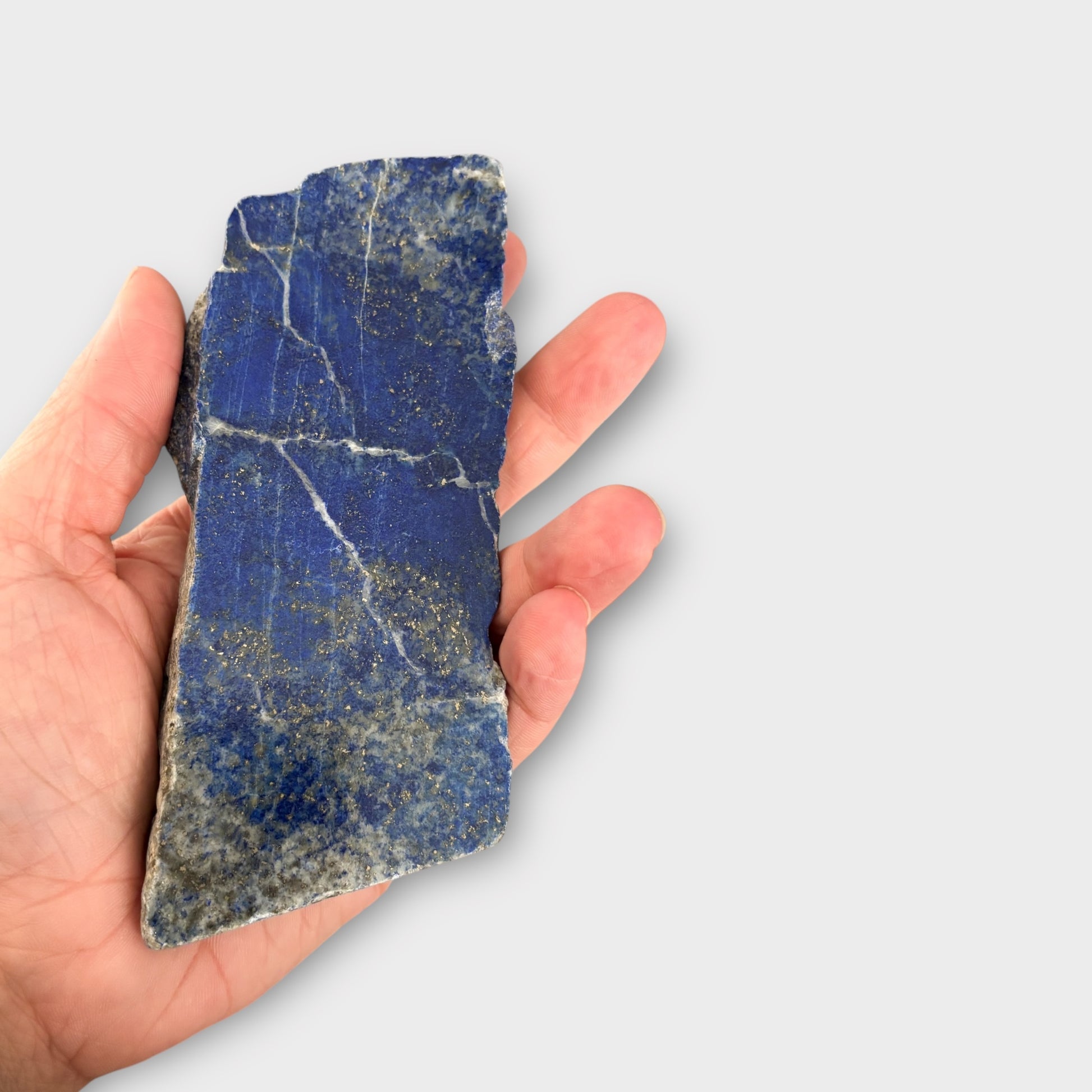 Lapis Lazuli blue crystal slab held in hand, showing long shape and detail