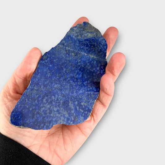 Lapis Lazuli crystal slab being held in hand for size and texture reference