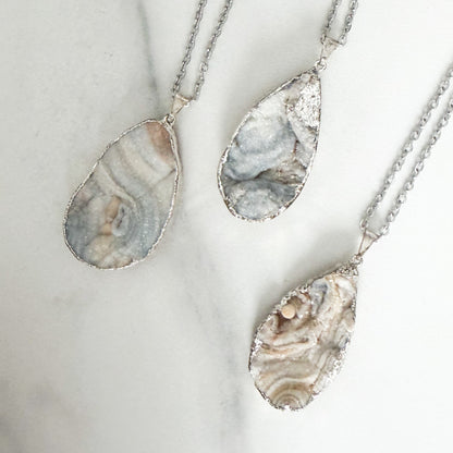 Light colored teardrop drusy pendant necklace with sterling silver plated setting on a stainless steel chain.