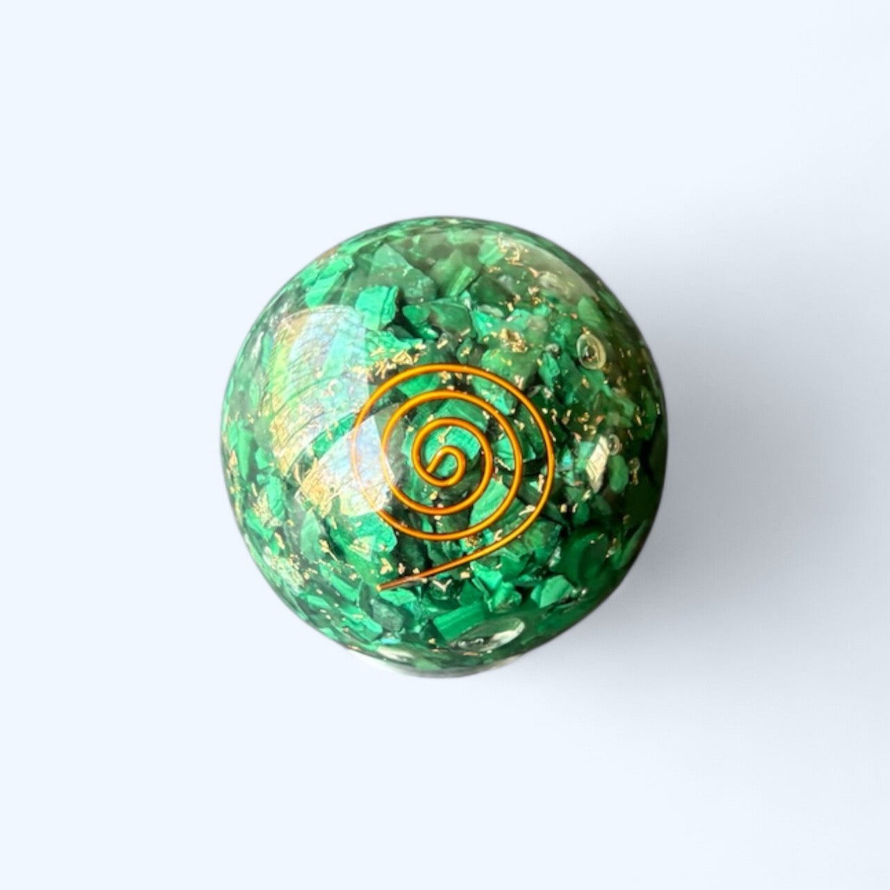 Polished green Malachite Orgone Sphere with copper spiral on light background