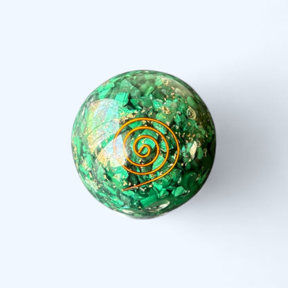 Polished green Malachite Orgone Sphere with copper spiral on light background