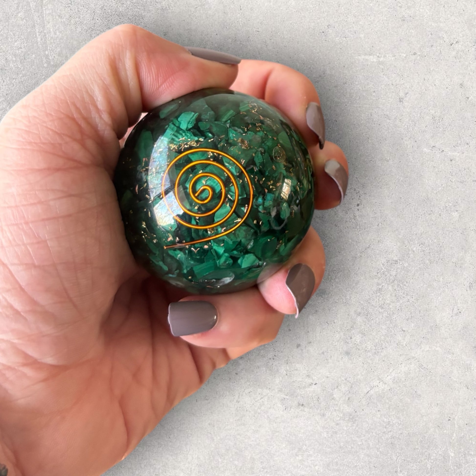 Malachite Orgone Sphere with copper spiral held in hand