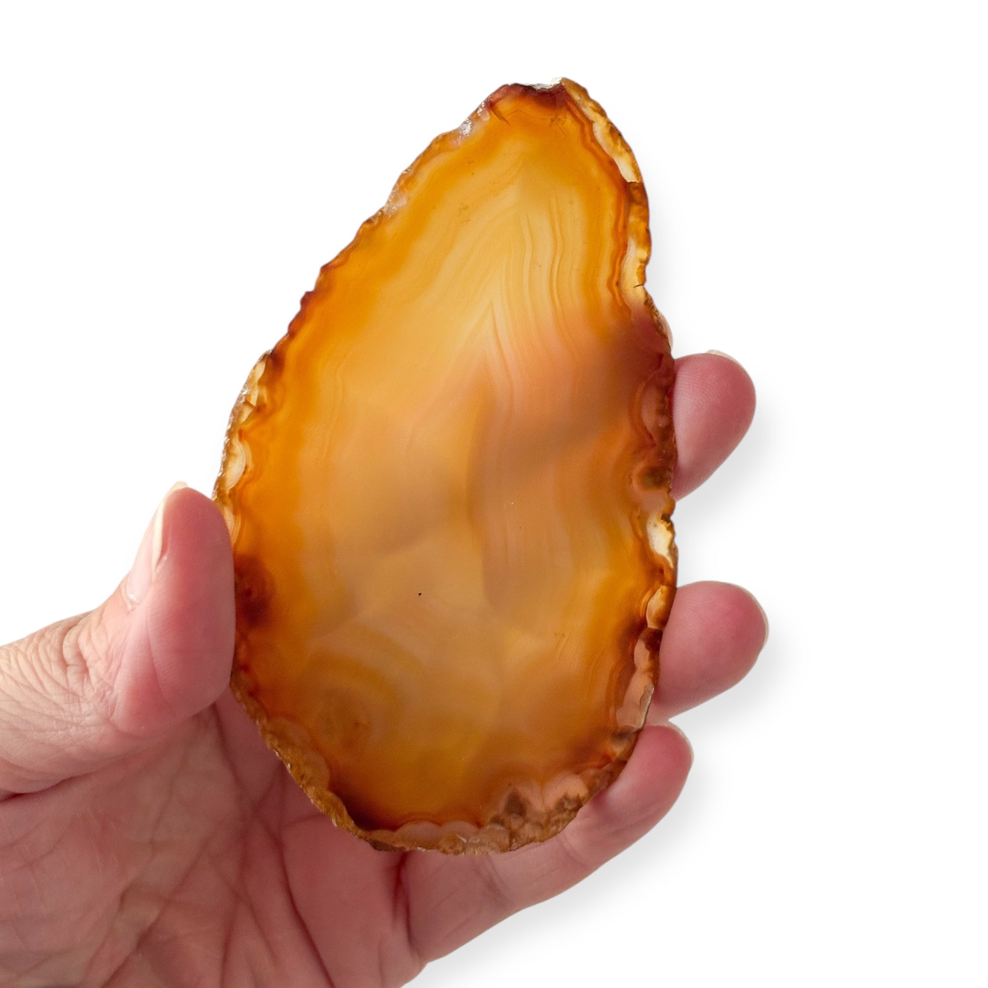 Hand holding golden yellow and orange agate slice