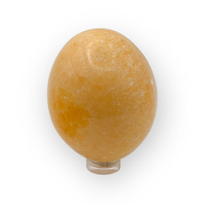 Polished Orange Calcite egg on stand showing warm orange hues and energizing crystal texture