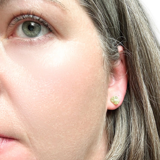A model wearing a pair of Peridot stud earrings to show size and texture