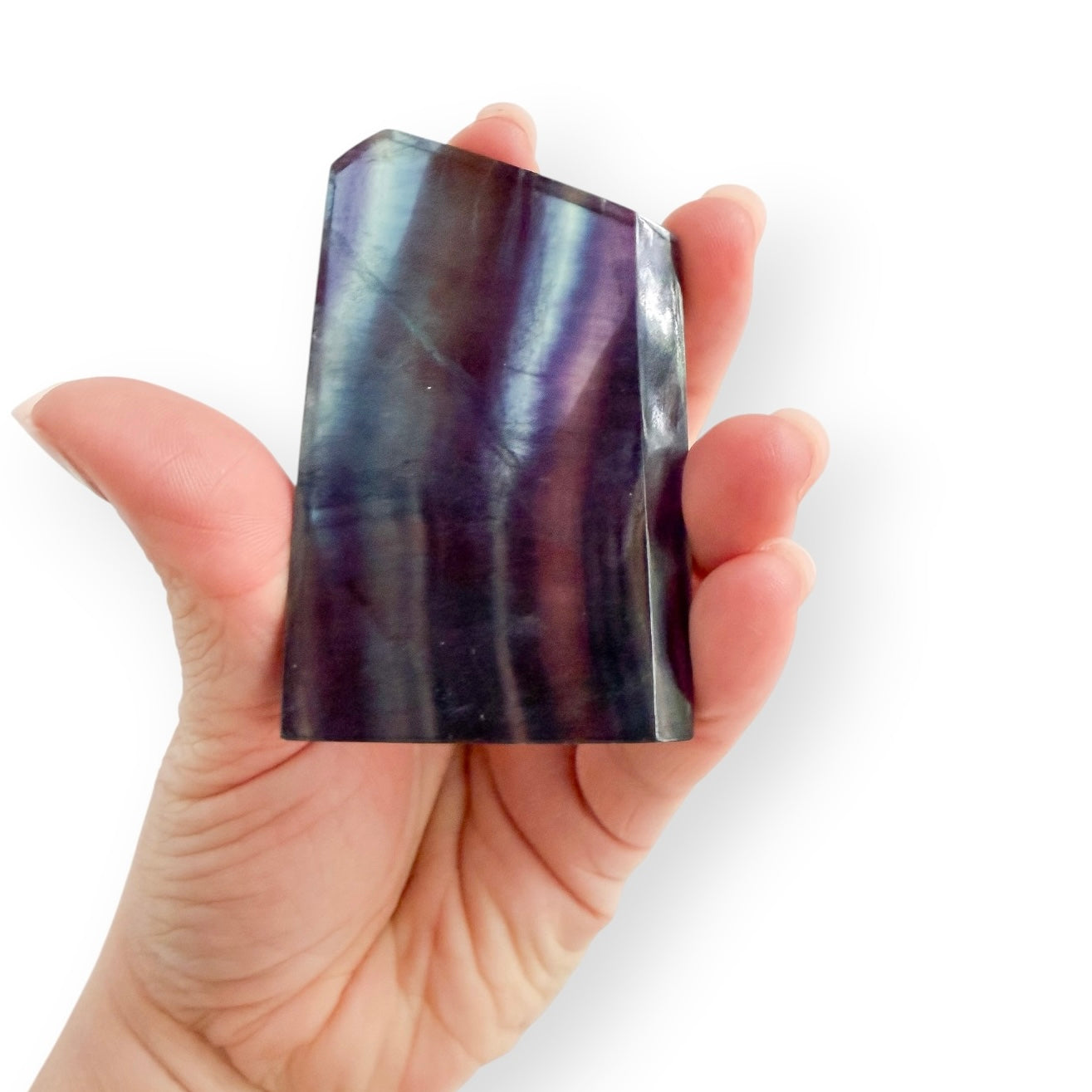Rainbow Fluorite slab held in hand showing vibrant purple, indigo, teal, and blue natural banding.