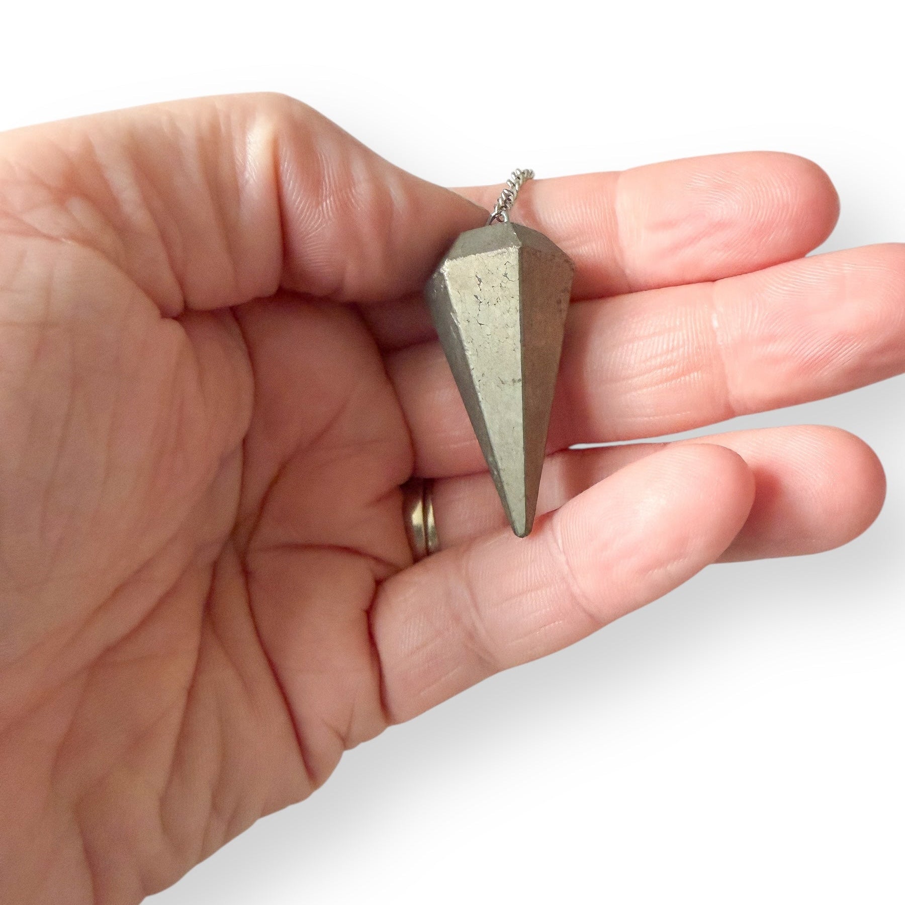 Pyrite crystal pendulum held in hand, metallic gold stone used for divination and energy guidance