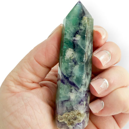 Green and purple Rainbow Fluorite crystal tower held in hand