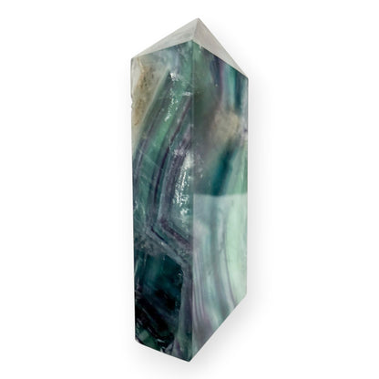 Side view of a polished Rainbow Fluorite crystal tower showing layered green and purple color zoning.