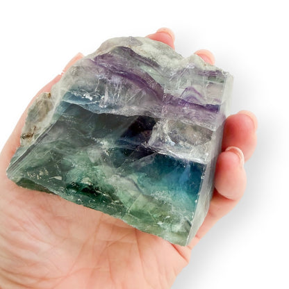 Rainbow Fluorite freeform held in hand for size reference, featuring polished and natural surfaces.