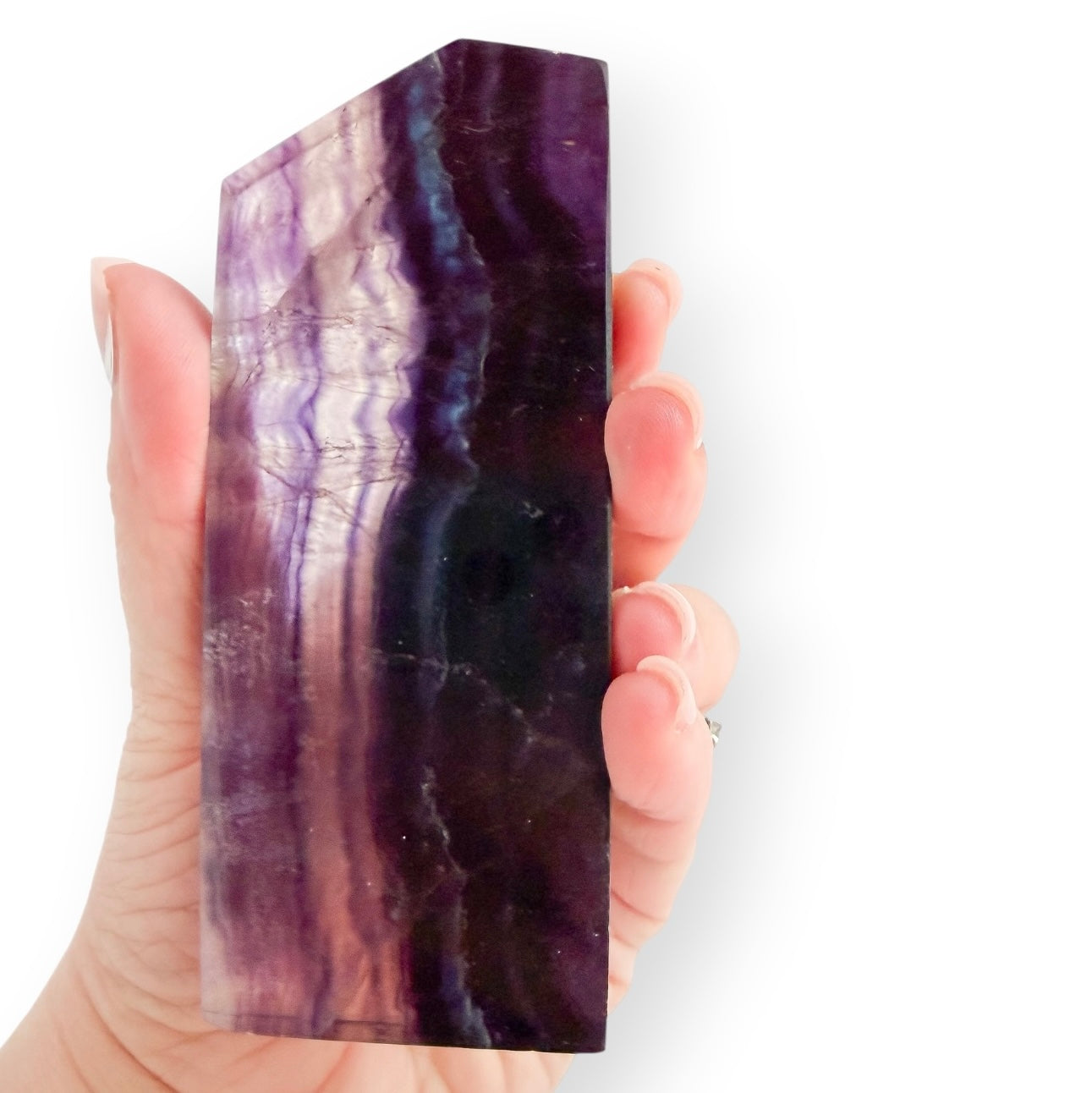 Large polished Rainbow Fluorite slab held in hand, showing vivid purple, indigo, and lavender bands.