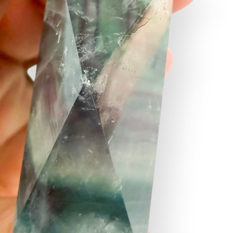 view of a Rainbow Fluorite point with deep green coloration, purple streaks, and polished surfaces.