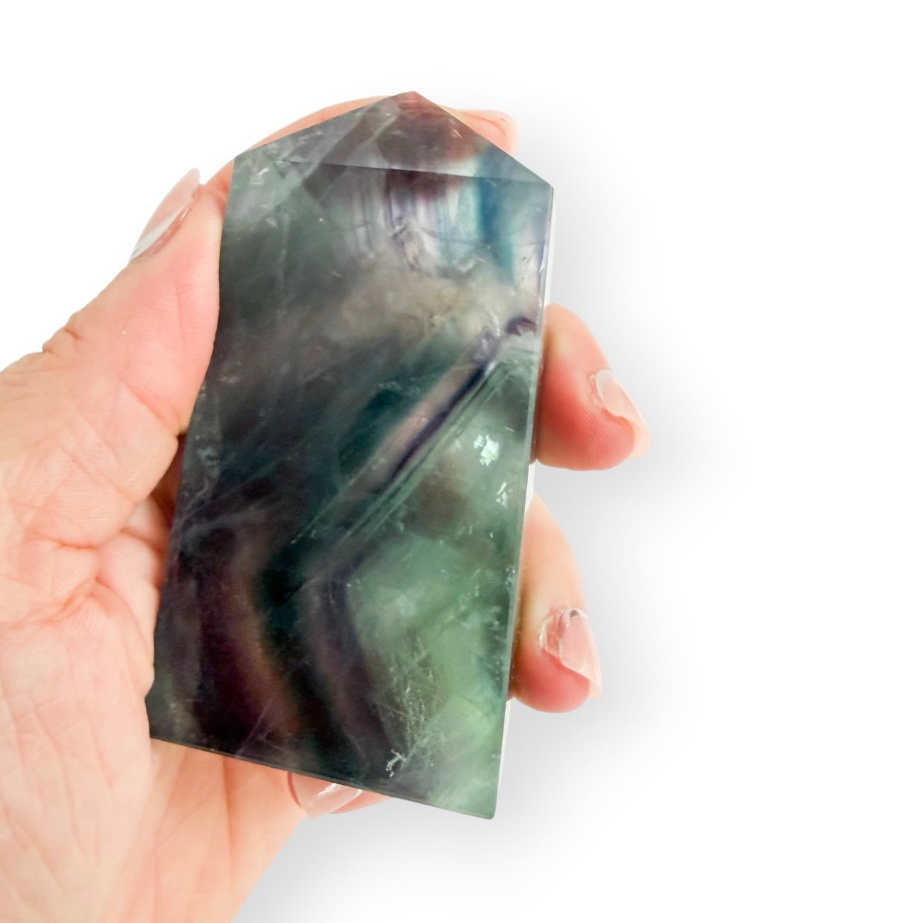 Rainbow Fluorite tower held in hand for size reference, displaying translucent green and purple bands.