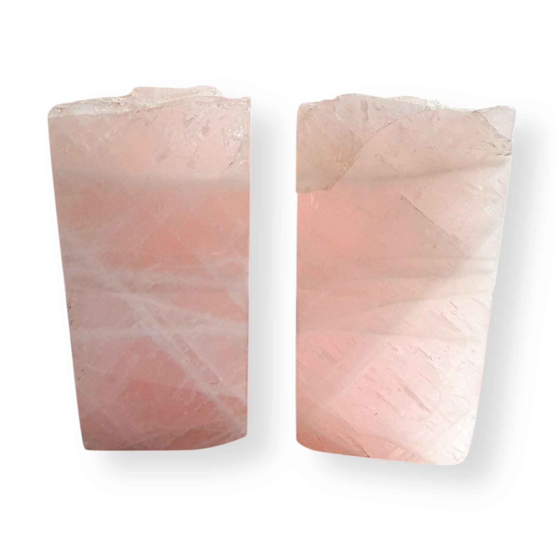 Side view of rose quartz crystal bookends showing natural stone texture and blush pink color tones.