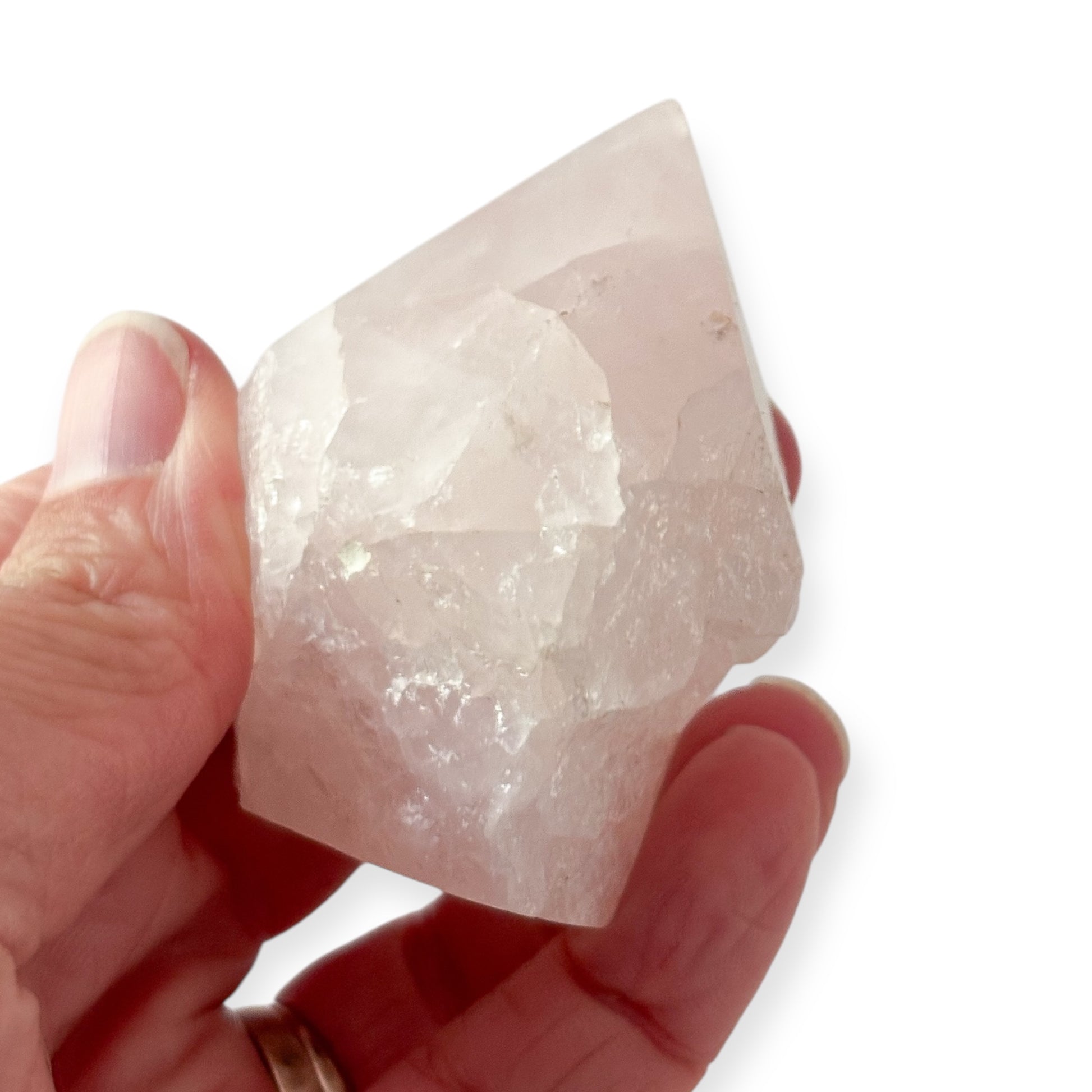 Hand holding Rose Quartz point showing blush pink color