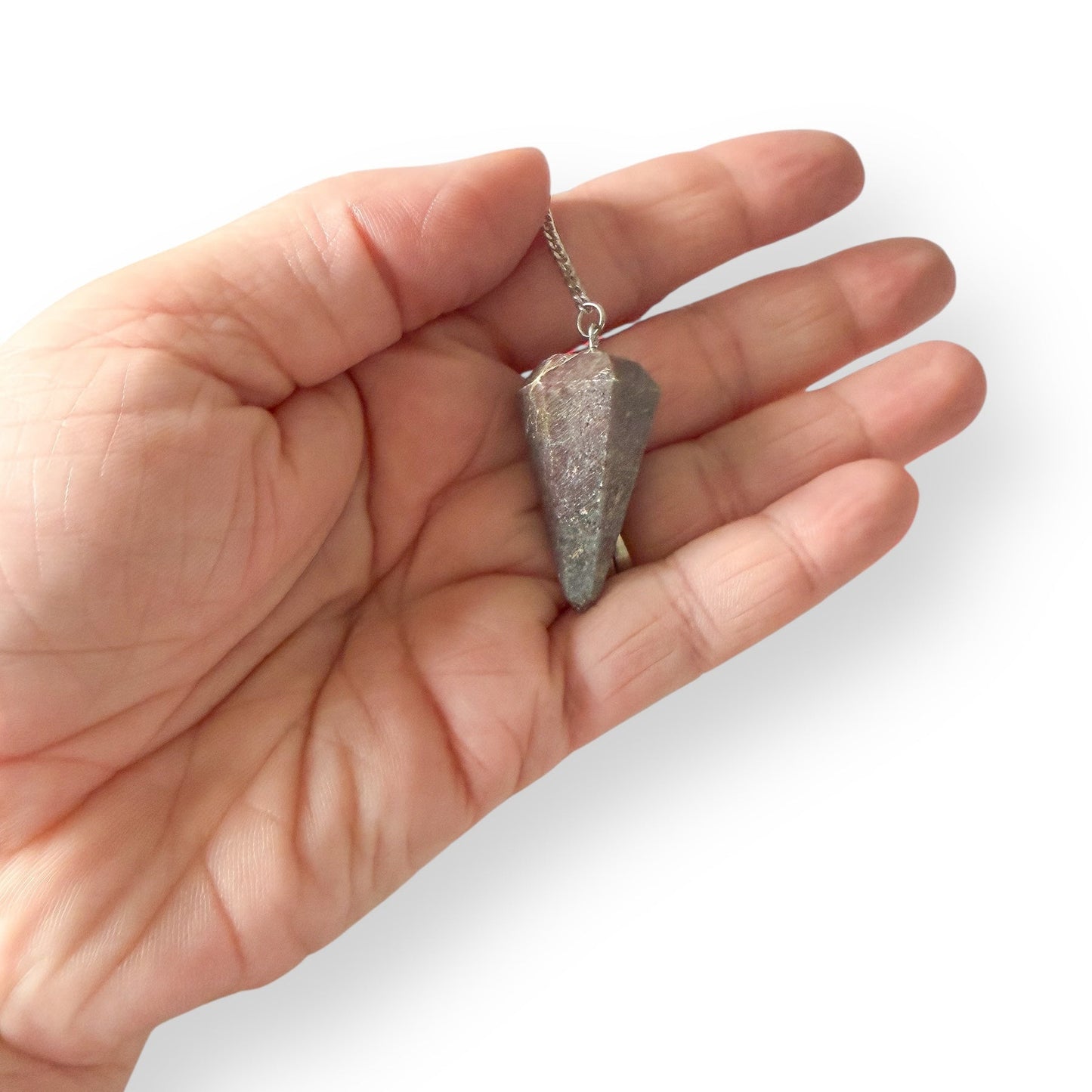 Hand holding Ruby in Kyanite pendulum on silver chain for intuitive guidance