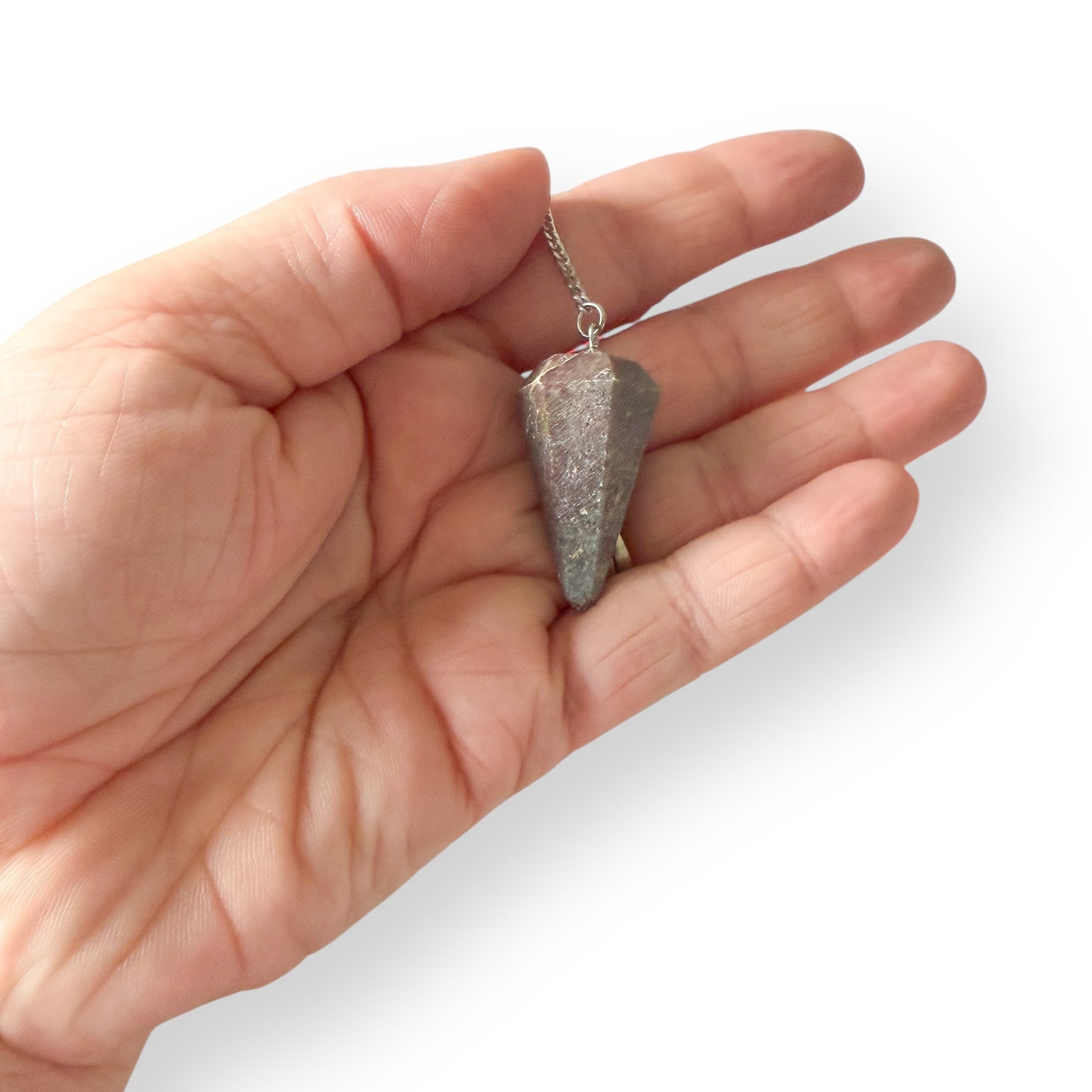 Hand holding Ruby in Kyanite pendulum on silver chain for intuitive guidance