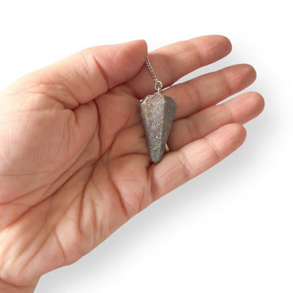 Hand holding Ruby in Kyanite pendulum on silver chain for intuitive guidance
