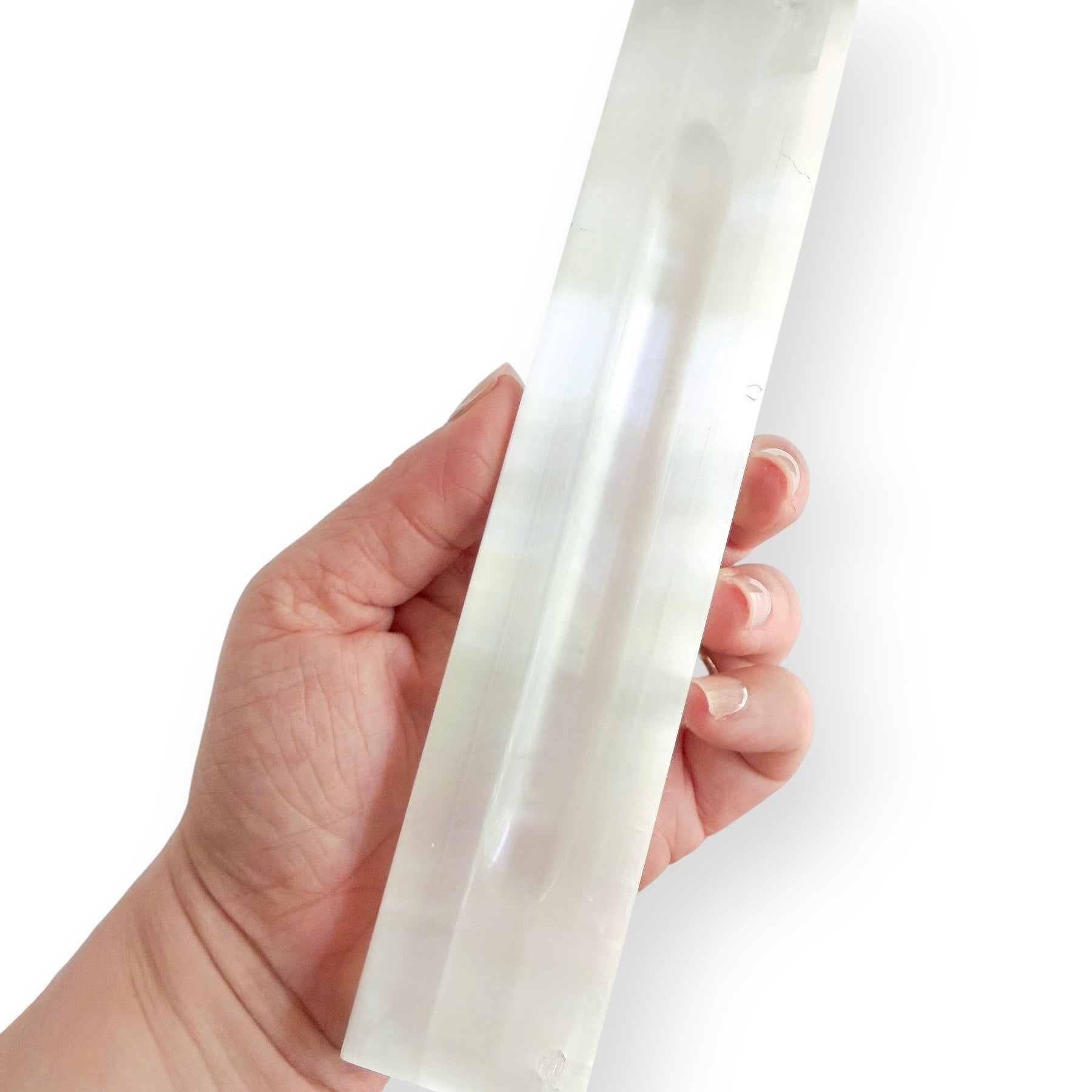 Hand holding a satin spar selenite crystal charging bar showing size and polished finish.