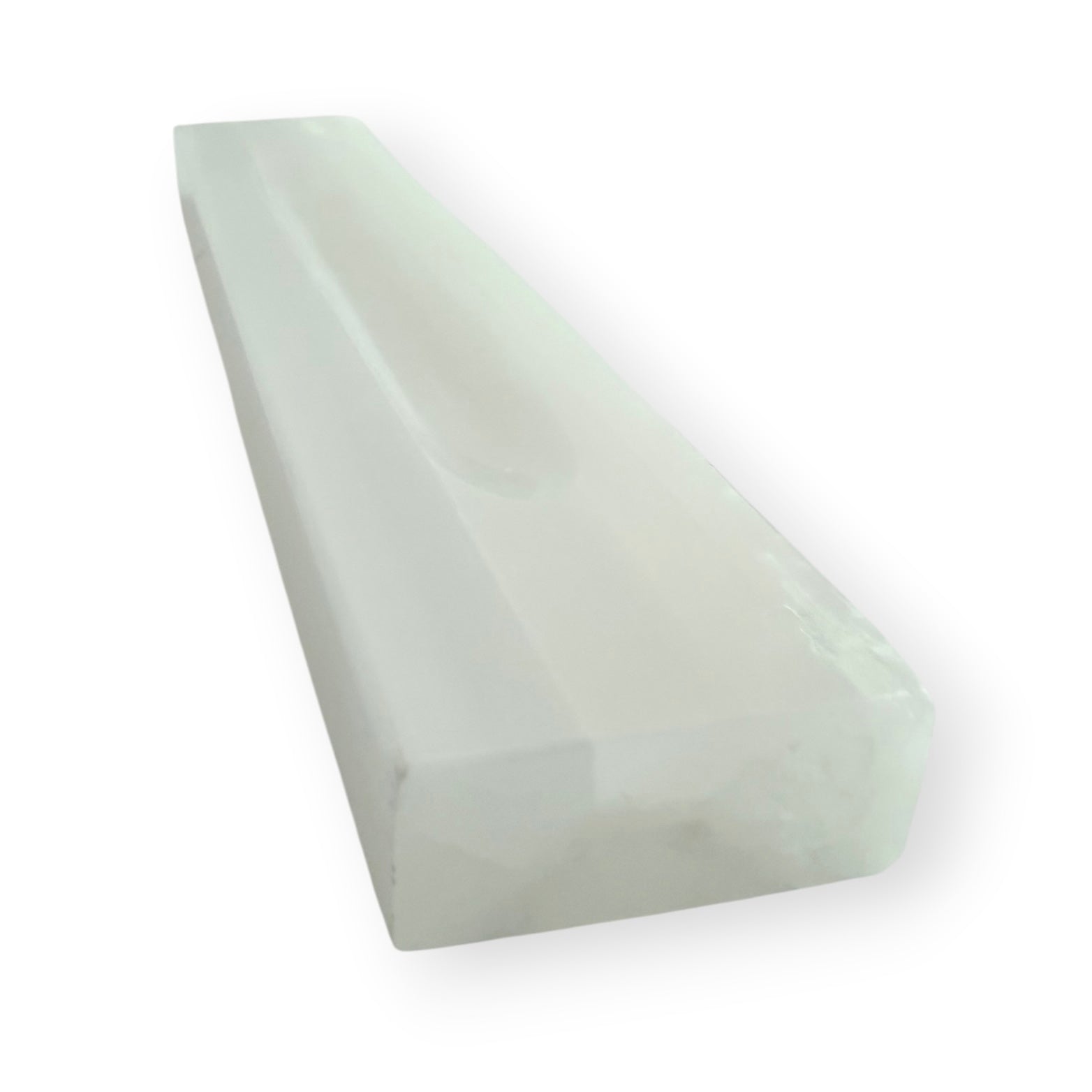 Angled view of a satin spar selenite charging bar with carved channel for crystals and jewelry.
