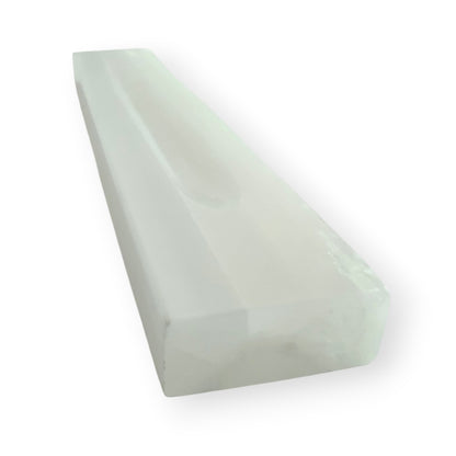 Angled view of a satin spar selenite charging bar with carved channel for crystals and jewelry.