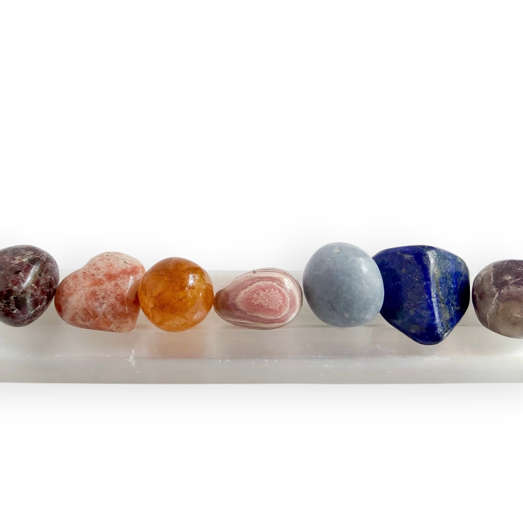 Satin spar selenite charging bar displaying polished crystal hearts, palm stones, and tumbled stones.