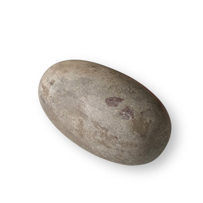 Shiva Lingam Stone B displayed on surface, highlighting natural color variations and balanced shape.