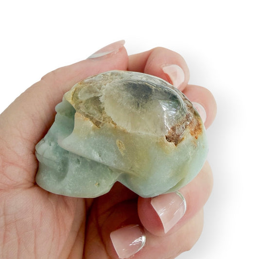 Side view of Caribbean calcite hand carved skull in hand to show size and detail.