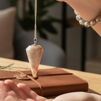 Sunstone crystal pendulum with warm peach and gold tones used for intuitive guidance and clarity during a quiet ritual
