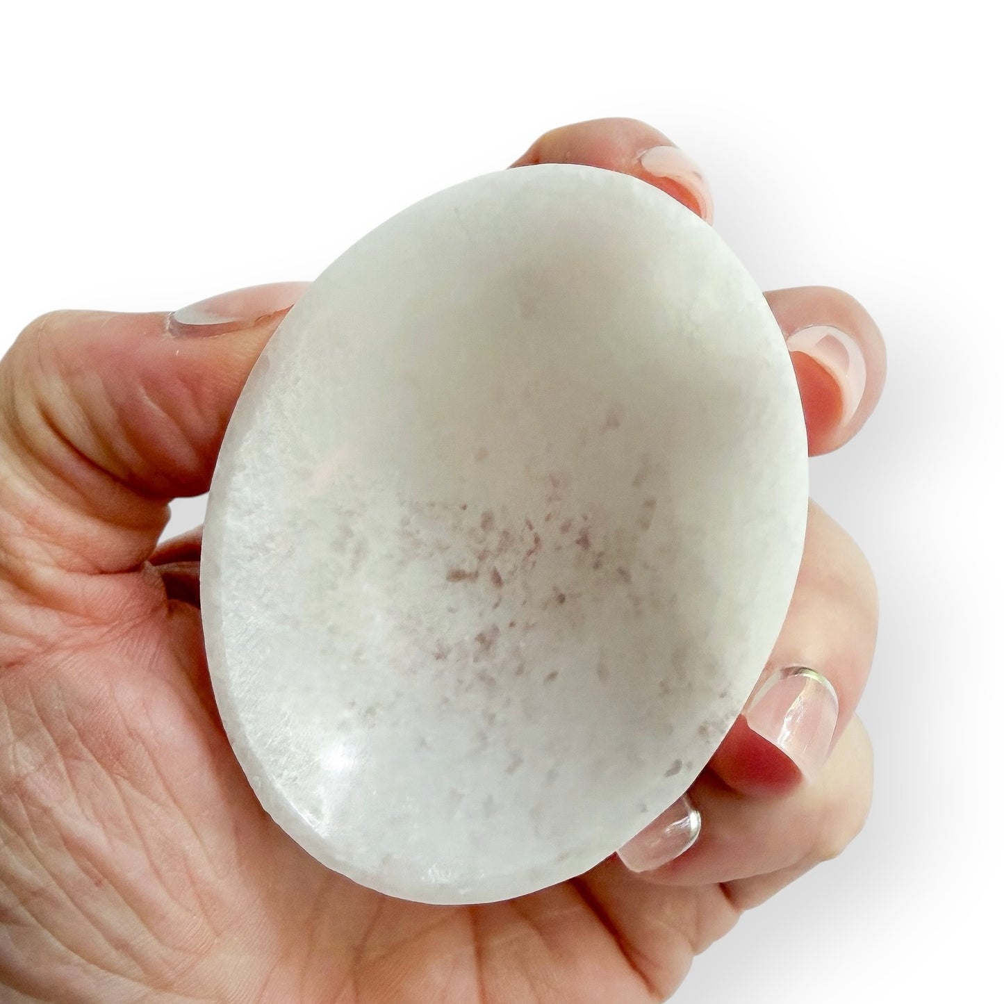 Handheld white Satin Spar oval bowl carved from natural crystal with a smooth polished finish.
